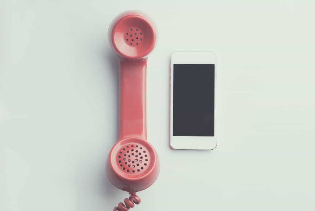 An old red phone lying next to a white smartphone.