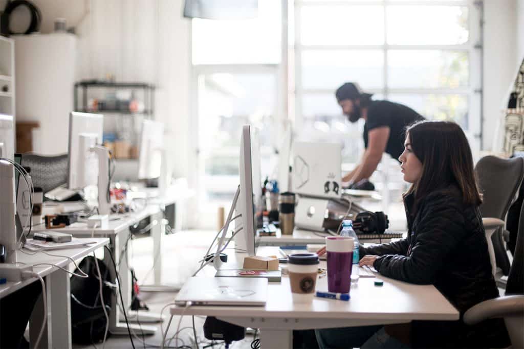 A woman working at her desktop in a busy open office.