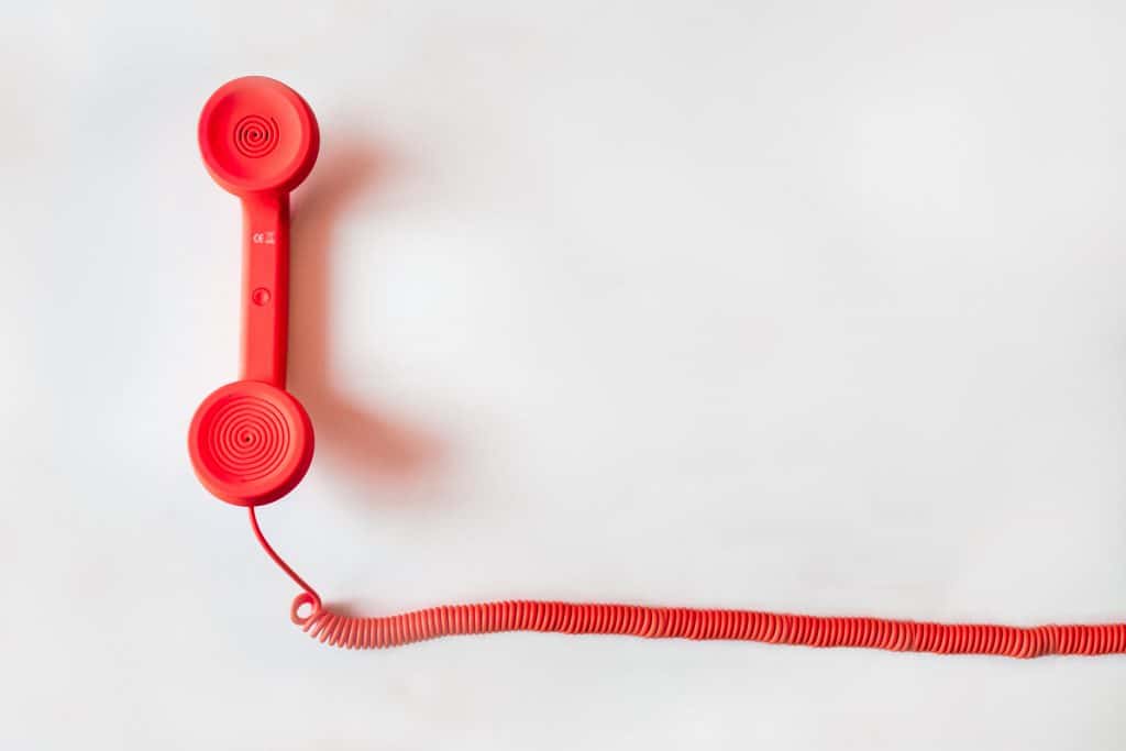 A bright red landline phone on a white background. 