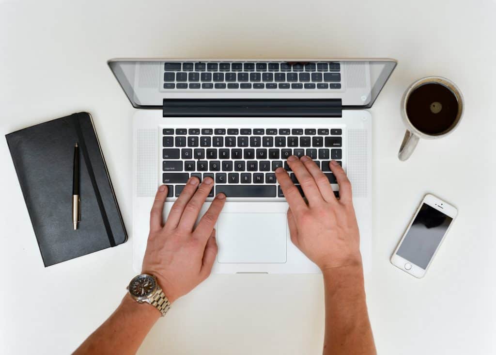 A person typing on their laptop with the essentials.