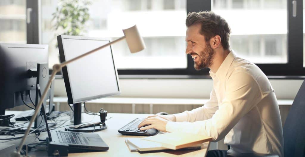 A man happily working in a new productivity routine at his desk. 